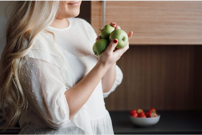 una donna tiene in mano 3 mele